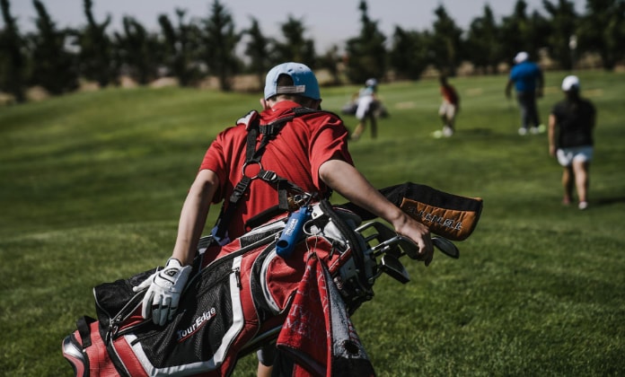 Boy carrying golf clubs