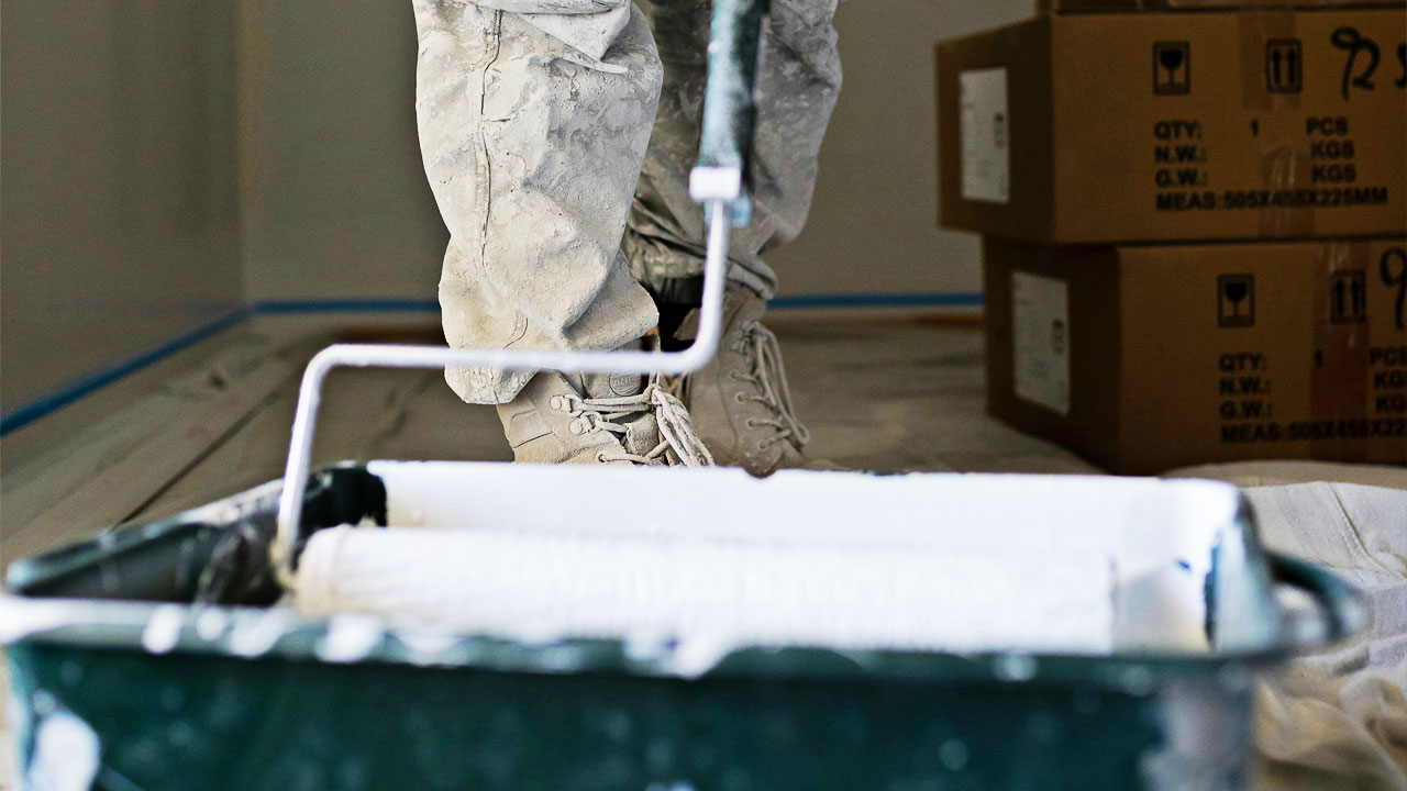 Someone putting white paint onto a roller